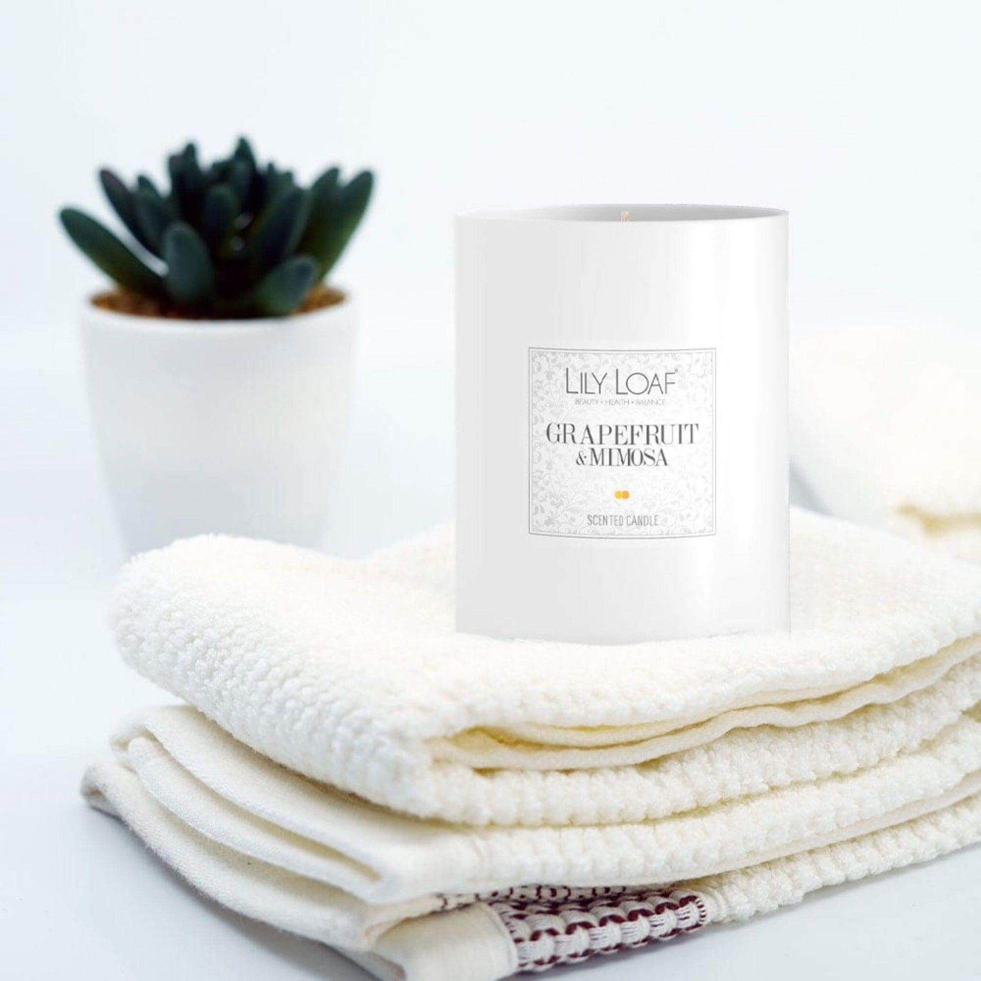 Grapefruit and Mimosa Soy Wax Candle placed on fresh folded towels